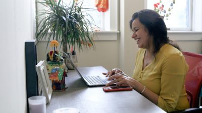 Shilpy Chatterjee, former Sakhi Senior Anti-Violence Program Manager, smiles as she works on her laptop.